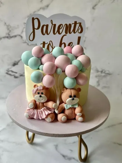 A heartwarming "Parents to be" cake for a baby shower. This design features two adorable teddy bears and a cascade of pink and blue fondant balls, perfect for a gender reveal or celebration.