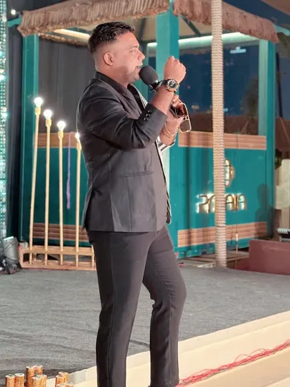 On stage, explaining a segment to the audience. Even from the side, the striped pattern of the blazer is eye-catching.