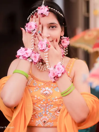 A playful and shy portrait of the bride peeking through her floral hand jewellery. This is a creative shot that highlights both her beauty and the intricate details of her look.