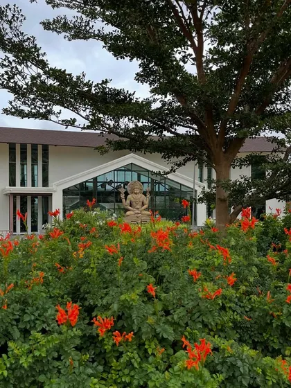 The vibrant orange flowers in our garden create a striking contrast with the green foliage and the main building, adding to the visual appeal of the retreat.