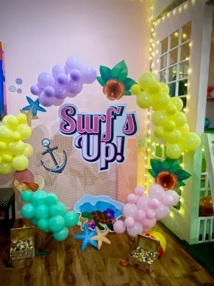Surf's up for a fun beach-themed party! The decor includes a custom "Surf's Up!" sign, starfish, and colorful balloons to create a tropical vibe.