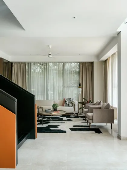 This view from the staircase landing shows how we compose spaces with an eye for balance and flow. The living area below feels open and connected, with a bold orange accent on the staircase adding a surprising touch of color to the otherwise neutral and minimalist interior.