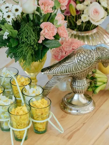 A table detail featuring a silver parrot and small glasses of flowers, adding a touch of Indian heritage to the decor.