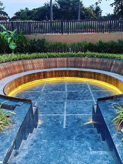 The combination of stone, wood, and light in this seating area creates a sophisticated and modern hardscape feature.