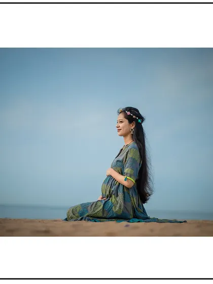 A serene solo portrait on the beach, with the mom-to-be sitting peacefully and looking out at the water.