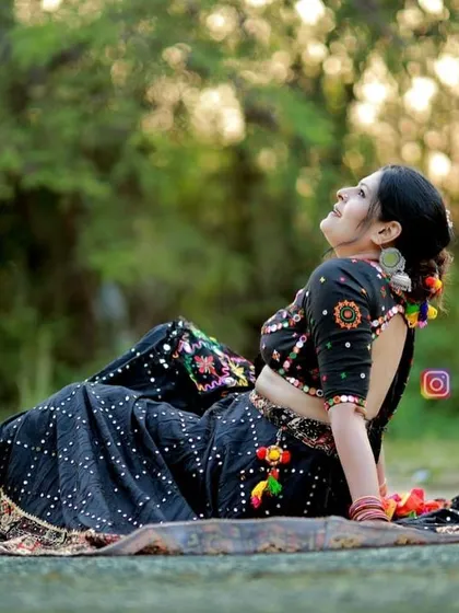 A candid moment in my custom black Navratri lehenga, featuring colorful embroidery and mirror work.