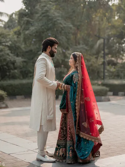 A beautiful portrait of the couple standing together, framed by the bride's long, flowing red veil.