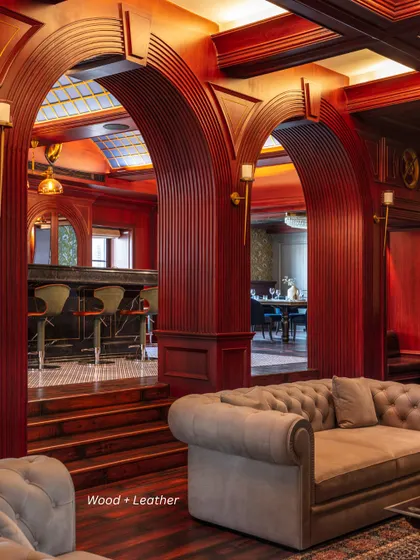 Luxury is created through the artful pairing of materials. Here, deep red fluted wood arches and a classic Chesterfield sofa create a rich, tactile experience, demonstrating our philosophy of building atmosphere through contrast and texture.