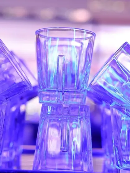 An artistic shot of stacked glasses at the bar, glowing under the purple party lights. I look for these creative compositions to add visual interest to the event gallery.