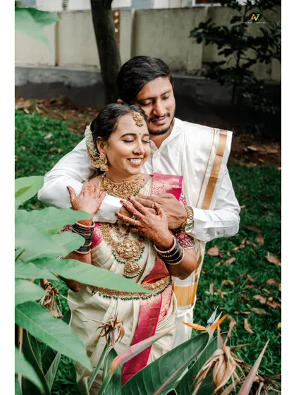 A romantic embrace, with the couple framed by green leaves, creating a natural and intimate portrait.