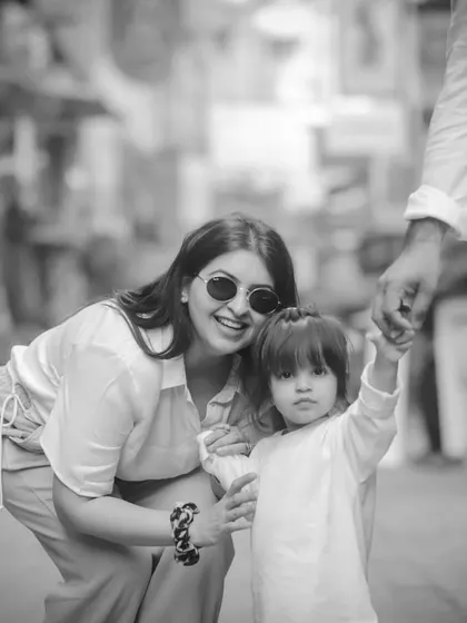 A black and white shot of a mother and daughter holding hands, with dad nearby. A candid moment from their family day out.