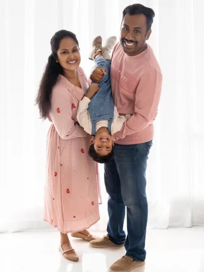 A joyful family moment, with the parents playfully holding their son upside down.