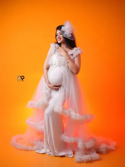 A joyful and radiant solo portrait. The mom-to-be looks happy and confident in a beautiful white gown against a bright yellow background.