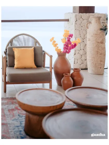 A mix of textures and materials, with wooden coffee tables, terracotta vases, and a woven armchair creating a sophisticated, earthy look.