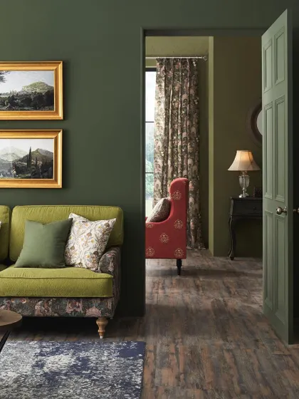 A view through a doorway into a richly decorated living room. This layered composition creates a sense of depth and discovery, showcasing how different fabric patterns and colors can coexist beautifully within a heritage-inspired theme.