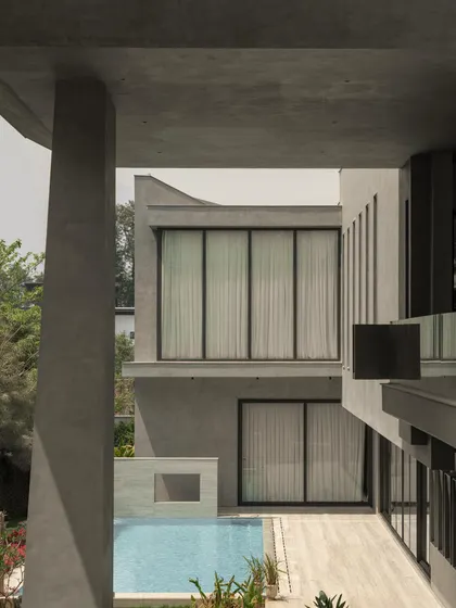 Views of the home from the garden, showing how the monumental concrete forms are softened by the surrounding greenery. The design creates a constant interplay between the architecture and the landscape.