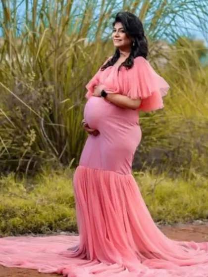 An outdoor shot of the same peach mermaid gown, showing how the long train looks in a natural setting. The soft color and flowing fabric create a romantic, ethereal vibe.