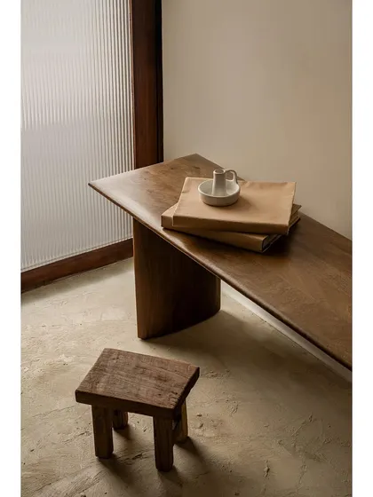 We incorporated elements of rustic, earthy design to ground the luxurious feel of the space. A solid wood bench with a live edge and a simple, rough-hewn wooden stool provide a tactile contrast to the smooth, polished floors and walls.