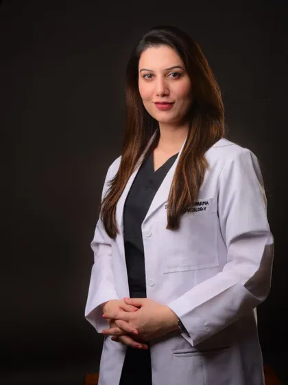 A professional portrait of a doctor in her white coat. The dark background and professional attire combine to create an image of expertise and trustworthiness.