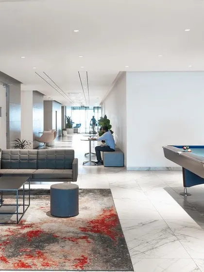 A recreational lounge in a tech office, featuring a pool table and comfortable seating. We believe that even breakout spaces should contribute to a sense of calm, using a muted color palette and organized layout to provide a genuine escape from work-related stress.