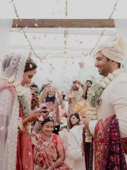 A shower of petals rains down on the couple during their varmala exchange, creating a beautiful and memorable photograph.