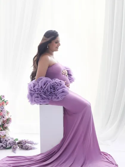 A serene side profile in a beautiful lilac gown. This pose elegantly showcases the baby bump while the soft fabric and color add a touch of romance.