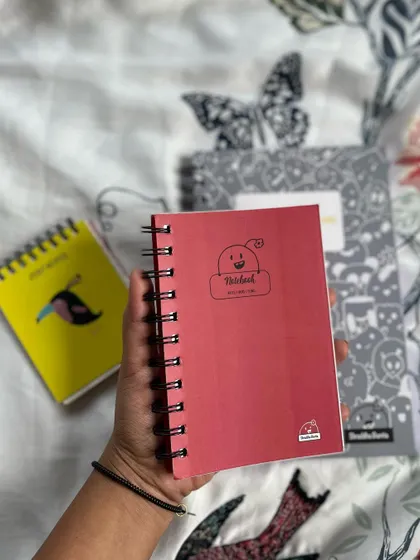 Holding one of the 6x4 inch notebooks to show its handy, portable size.