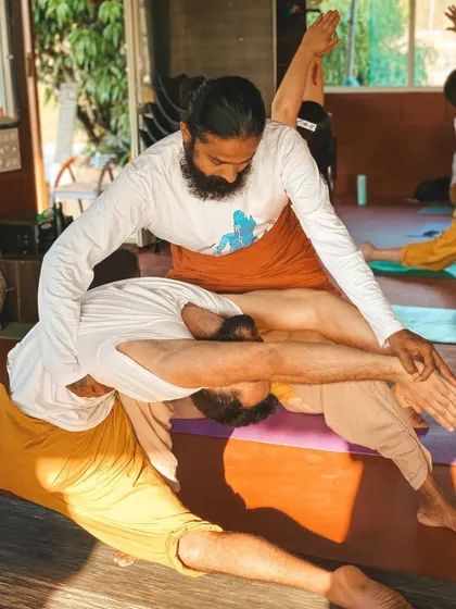 A hands-on adjustment in a deep stretch helps a student find new space in their body. This personalized guidance is central to our teaching philosophy, ensuring you understand the postures from the inside out.