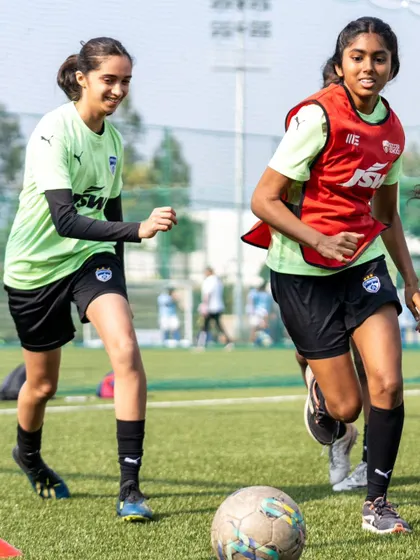 Two players from our girls' academy compete for the ball. We provide a platform for girls to develop their skills in a competitive setting.