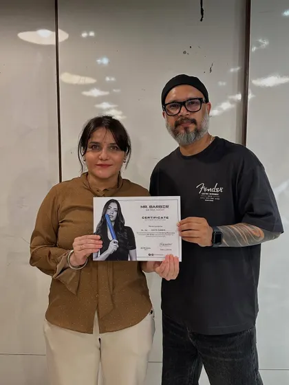 Certification is a major milestone. Here, a student proudly receives her certificate after completing an advanced haircut workshop with a visiting industry expert.