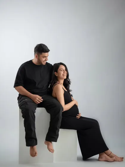 A modern and stylish couple's portrait in matching black outfits. The minimalist setup with white blocks creates a clean and contemporary feel.