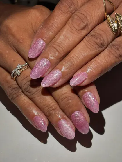 A beautiful set of almond-shaped nails with a soft pink glitter polish. This look is perfect for clients who want a touch of sparkle while maintaining a classic and elegant style.