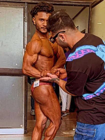 Backstage at the natural bodybuilding championship, I'm giving my client last-minute instructions on his posing.