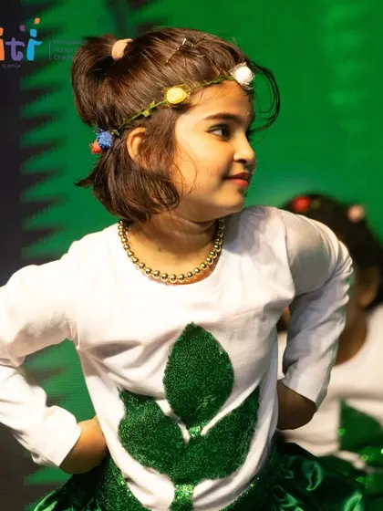 A girl with a floral headband smiles during her performance as a part of the vibrant life on Earth.
