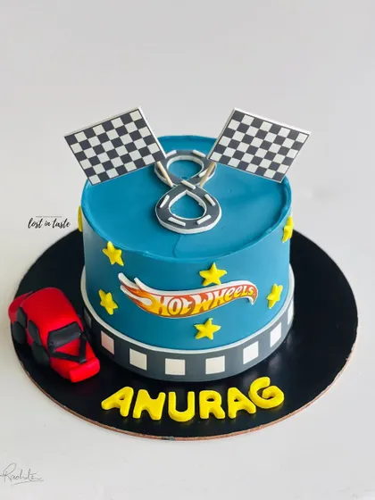 A Hot Wheels themed cake for a young racing fan. This design features a vibrant blue buttercream, the Hot Wheels logo, checkered flags, and a toy car.
