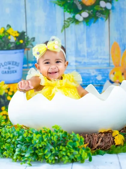 Posing happily in her Easter egg shell. The detailed backdrop with bunnies and flowers makes this a truly memorable spring portrait.