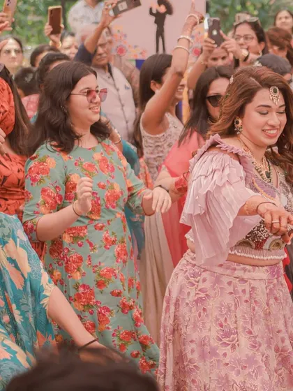 The bride leads the dancing at her Mehendi party. The event is filled with music and celebration, with all the guests joining in on the fun.