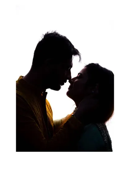 An intimate silhouette portrait. The focus is on the space between them, filled with anticipation and love, making it a powerful pre-wedding photograph.