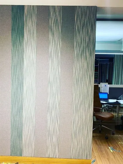 A finished wall with striped acoustic fabric, separating a workspace from a common area.