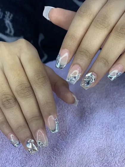 A stunning set of square nails with silver chrome accents and large, 3D silver embellishments.
