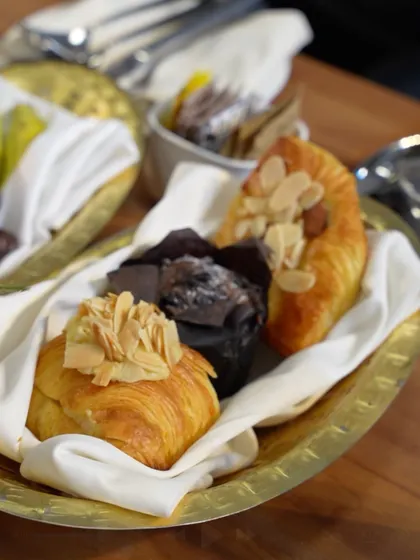 A basket of freshly baked croissants and muffins, part of a breakfast buffet. We offer a full range of bakery items, all made with the finest ingredients.