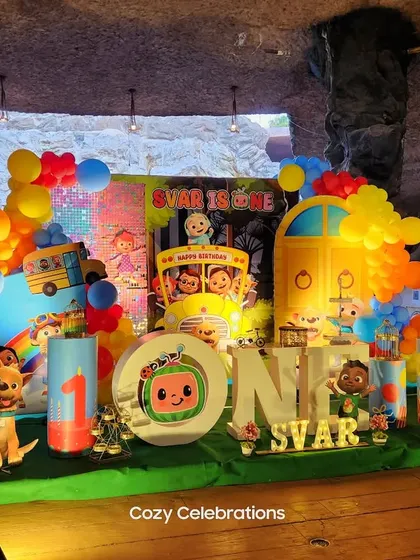 A full view of the Cocomelon "Svar is One" party, showcasing the detailed stage, character cutouts, and personalized milestone board.