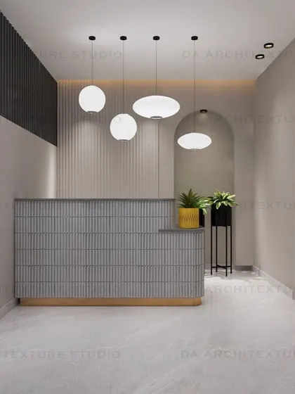The reception area of the office, with a modern fluted desk, statement pendant lights, and an arched mirror to create a welcoming first impression.