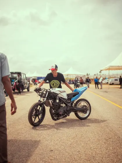 A participant pushes his stripped-down custom drag bike, a lightweight machine built for maximum acceleration.