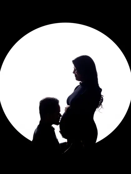 A classic and tender silhouette. The father-to-be gently kisses the baby bump, a gesture full of love and anticipation for the little one's arrival.