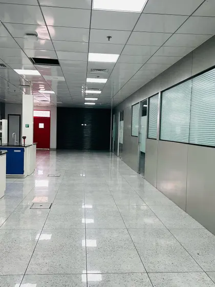 This hallway in a commercial facility features durable, easy-to-clean surfaces and access to specialized lab areas, indicated by the blue cabinetry. The design prioritizes functionality and workflow efficiency.