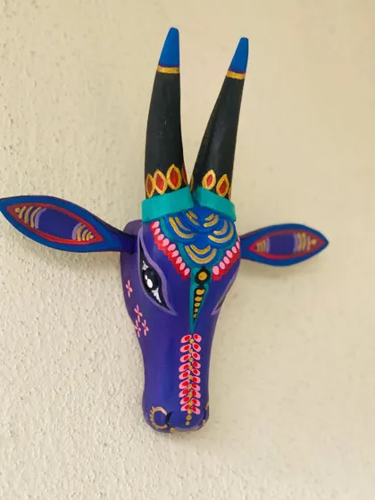 Mounted on a plain wall, the purple Nandi with its detailed ornamentation and expressive eyes becomes a piece of statement art.