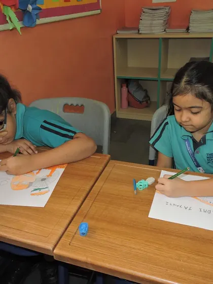 Two students work side-by-side, coloring images related to India's freedom struggle and national leaders.