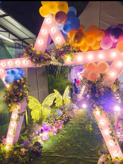 A unique star-shaped entrance arch with marquee lights. I decorated it with flowers and balloons for a fun, celebratory event.