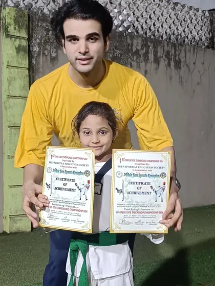 A student proudly displays her two certificates of achievement. Her hard work has clearly paid off.